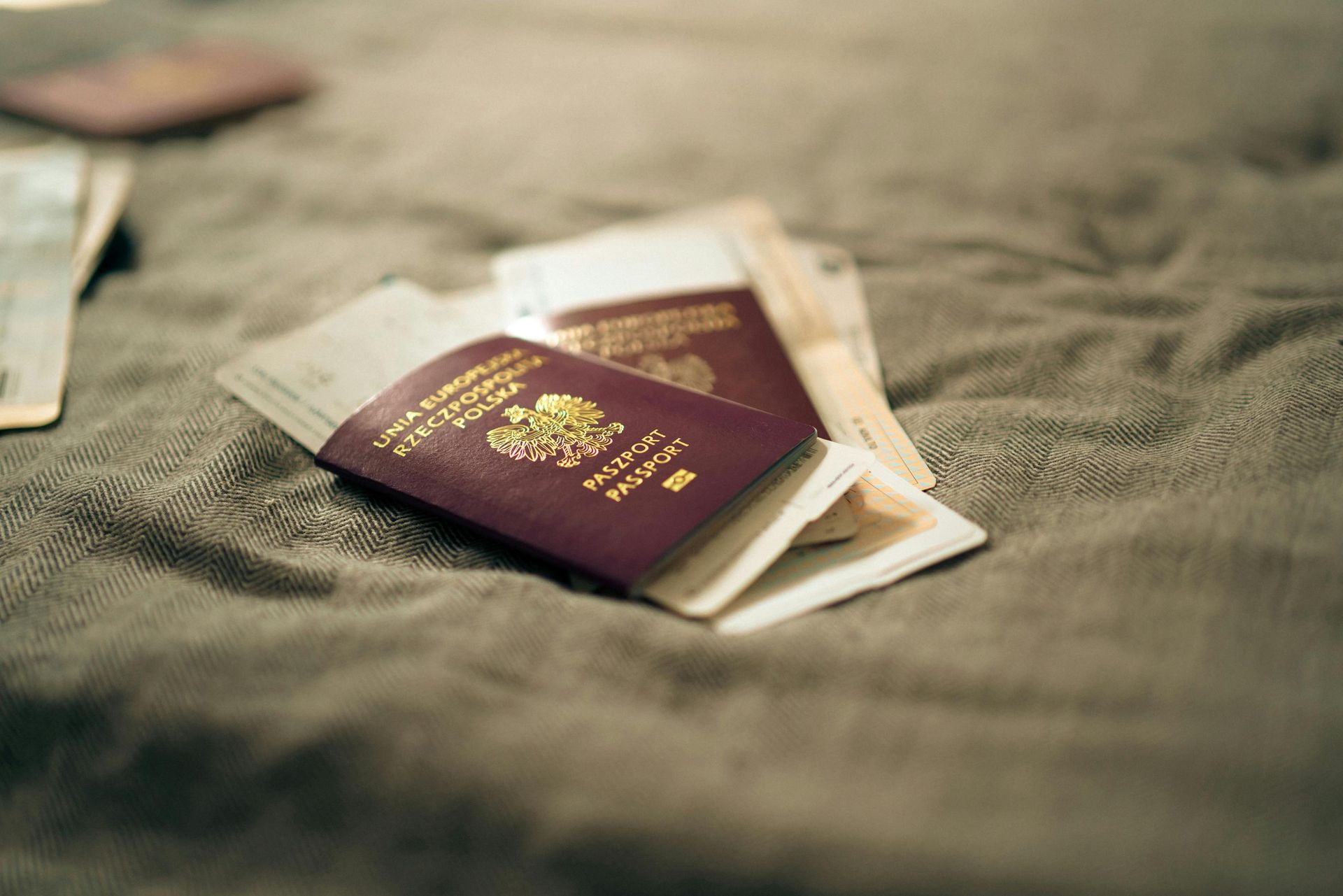 Due passaporti color bordeaux su una superficie di tessuto beige con fogli piegati sotto