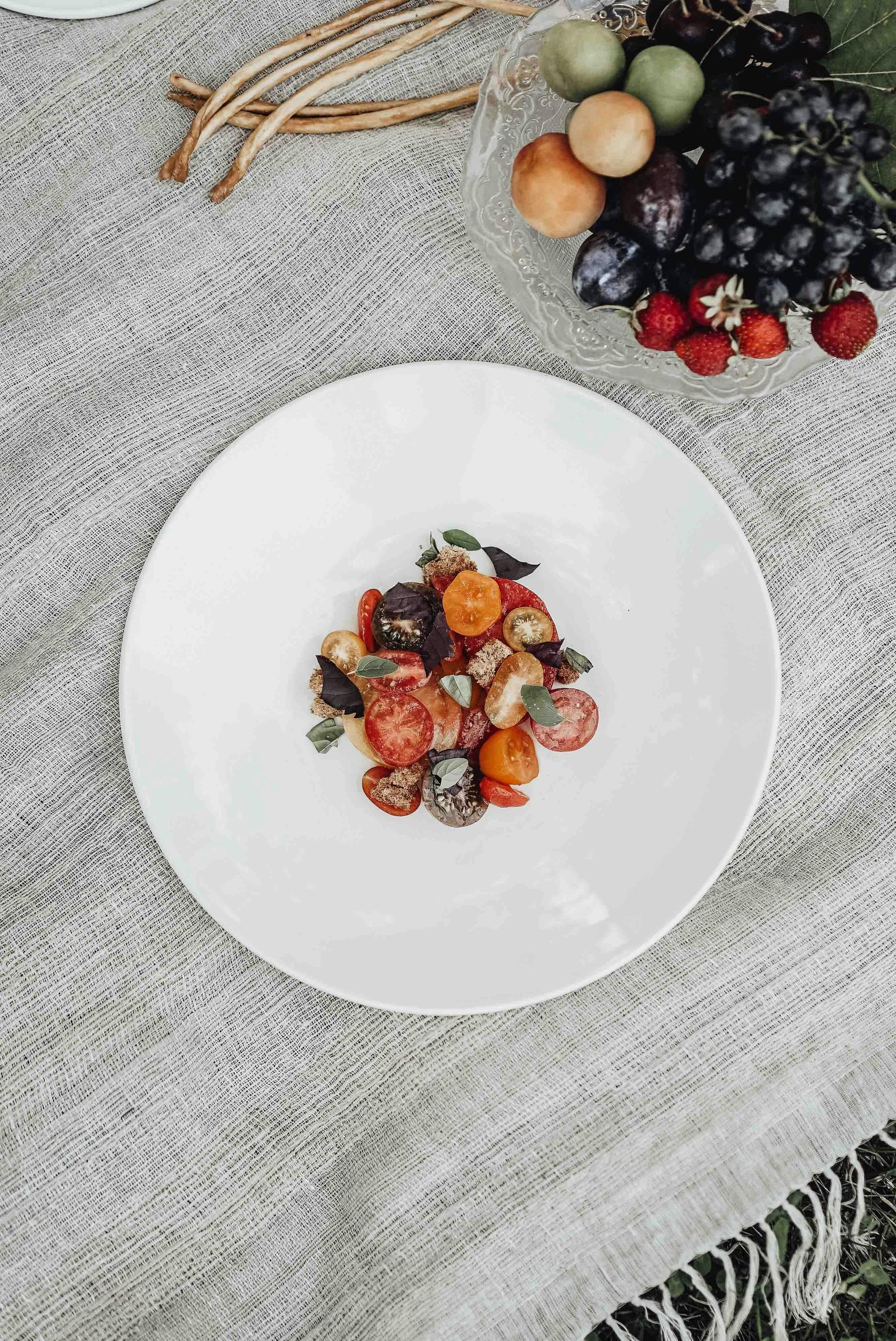 Piatto bianco con un piccolo dessert di frutti di bosco e frutta su una tovaglia dalla trama leggera