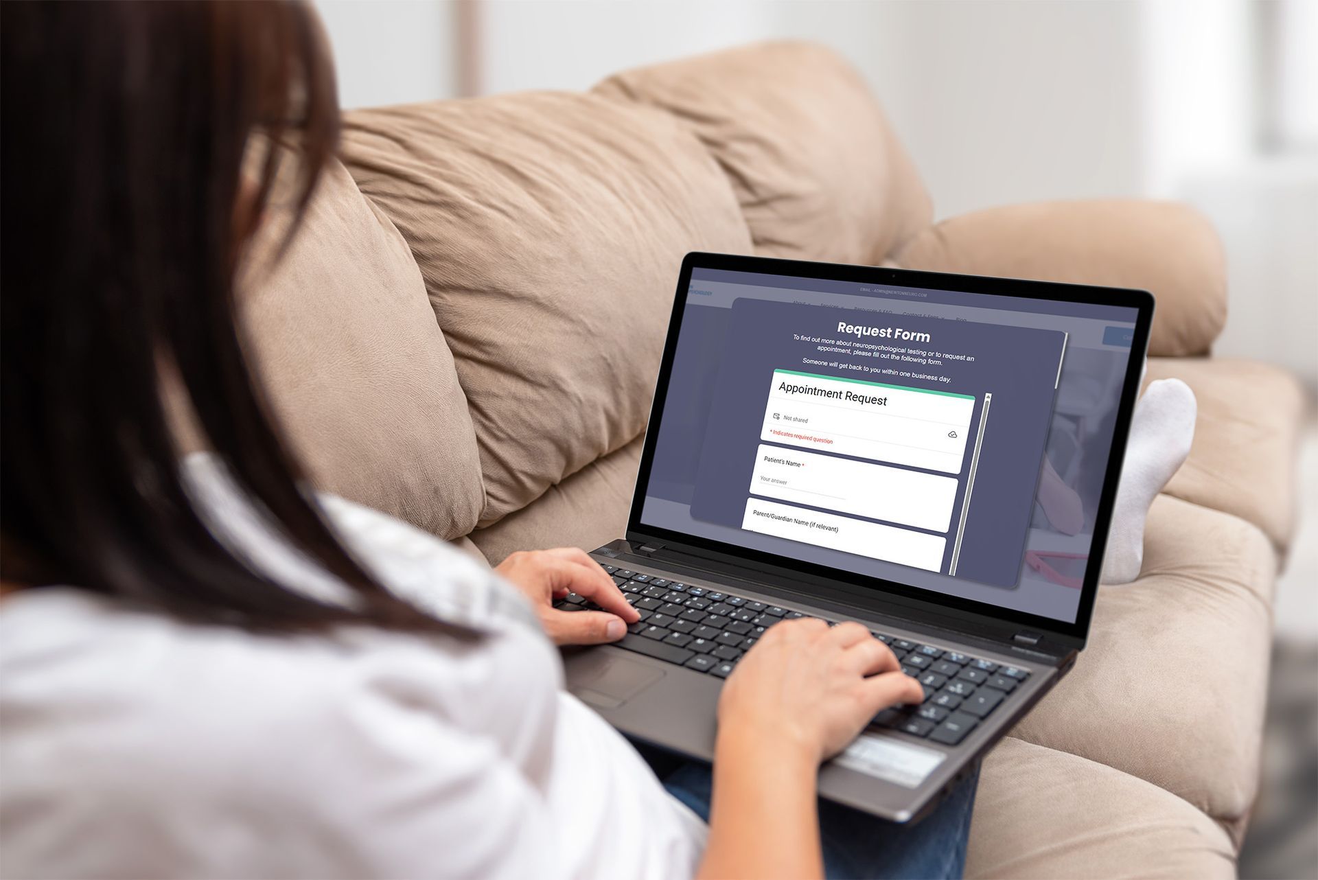Person using laptop on a couch; website form displayed on screen.
