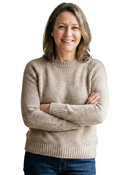 Woman with arms crossed, smiling, wearing a tan sweater and jeans.