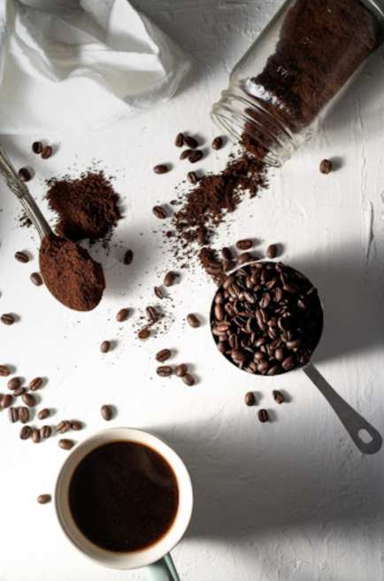 Coffee ingredients: beans, grounds, and a cup of coffee on a white surface.