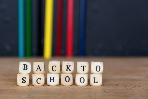 Letter blocks spelling “BACK TO SCHOOL” on a wooden surface with colorful pencils in the background