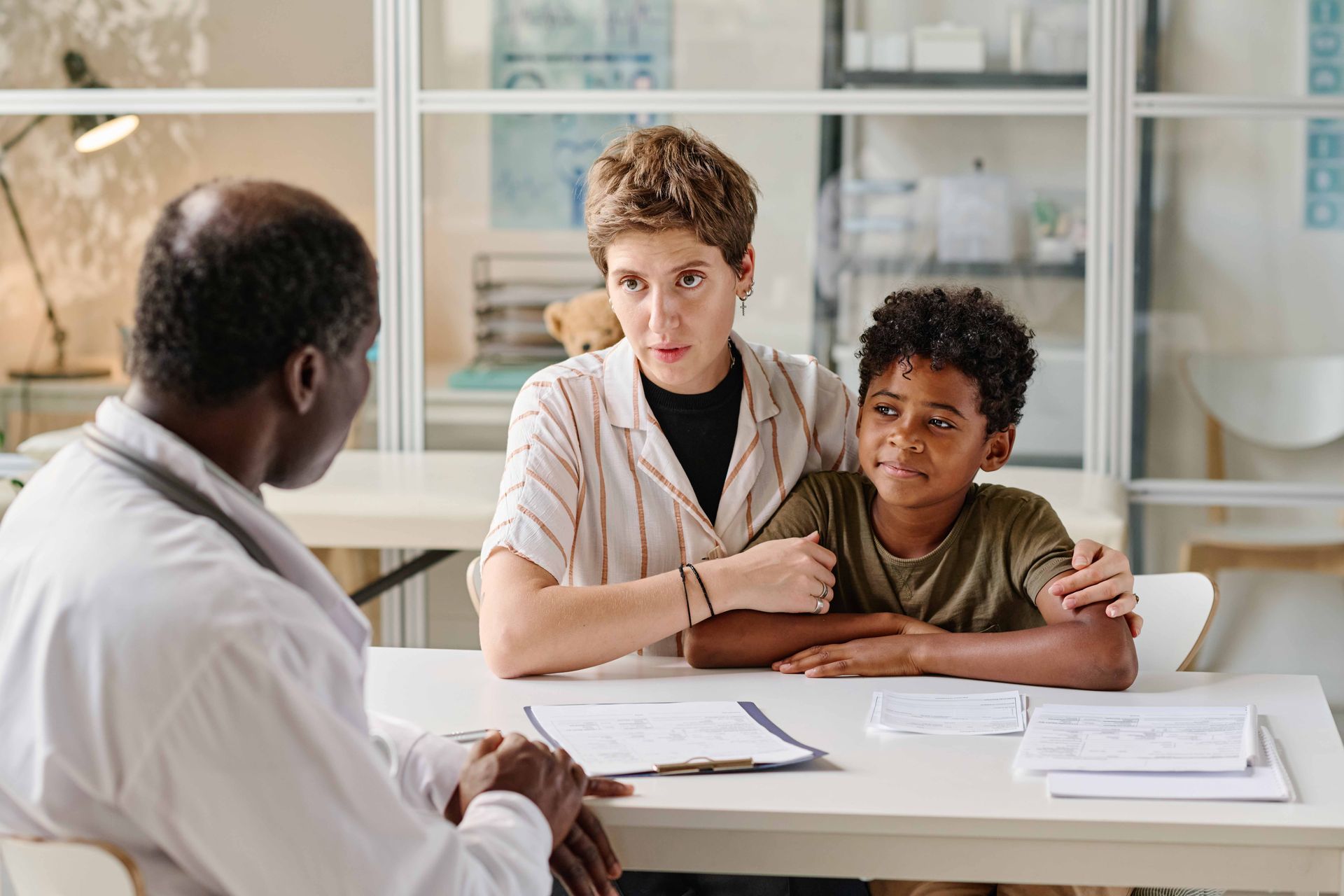 Doctor speaking with a woman and child at a table in a medical office.