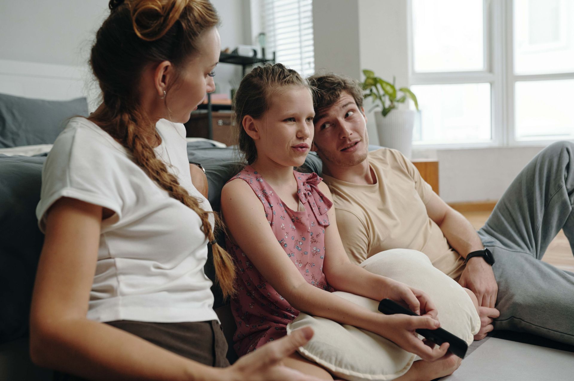 Family of three sitting on floor, having conversation. Woman, child, and man. Natural light.