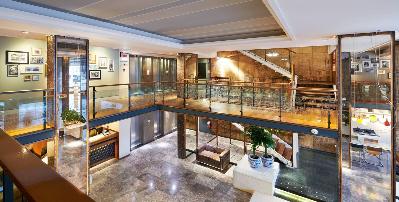 Interni moderni su più livelli con ringhiere in vetro, mattoni a vista e area salotto.