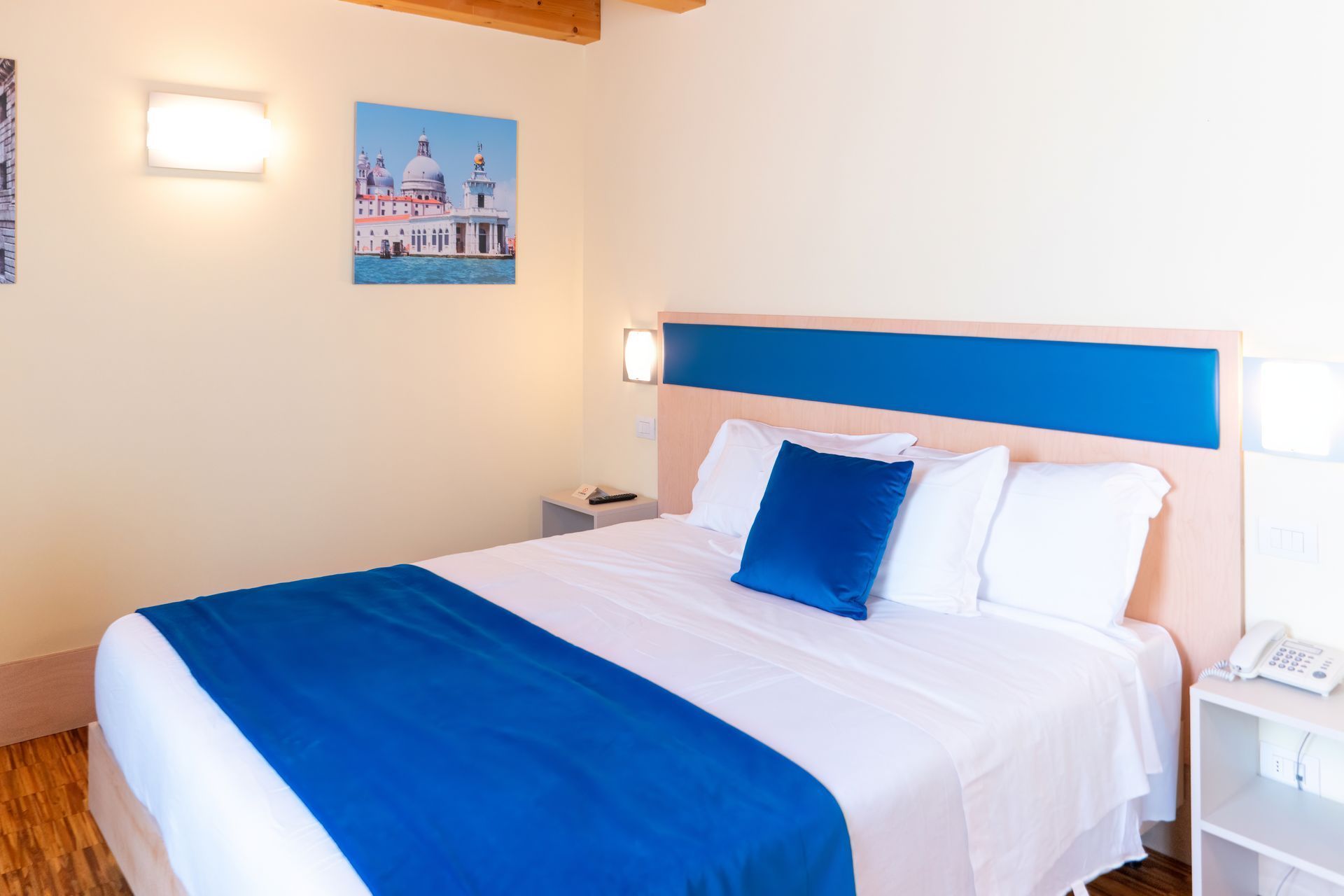 Camera da letto con letto, dettagli blu e opere d'arte alle pareti.