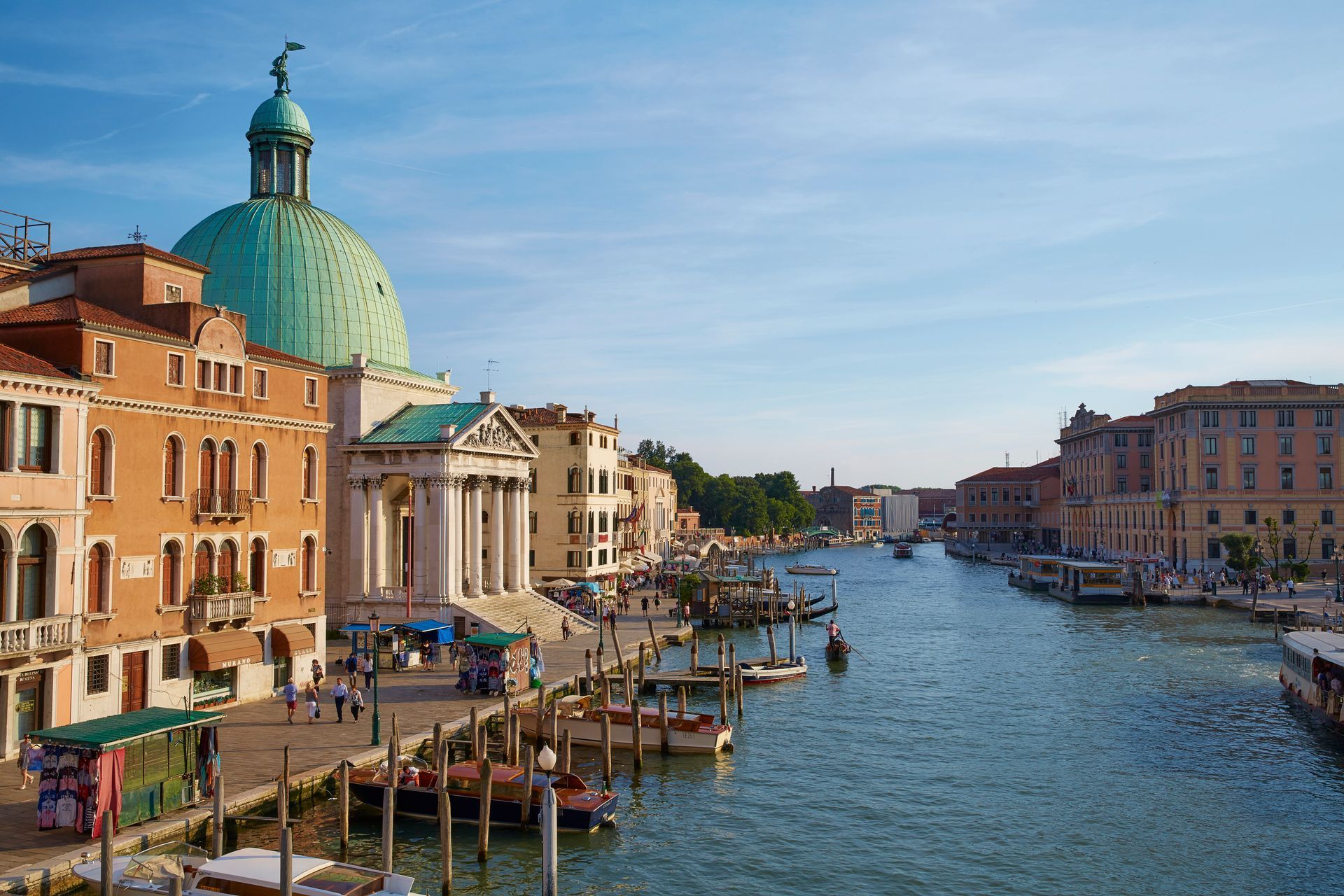 Canale di Venezia con edifici, barche e una chiesa con cupola in una giornata di sole.