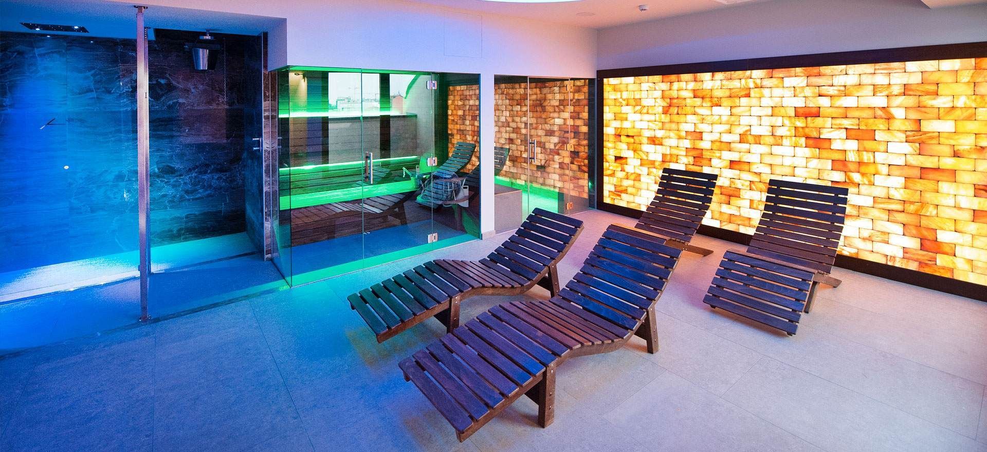 Una sala spa con sedie a sdraio in legno, una parete di sale e illuminazione blu.