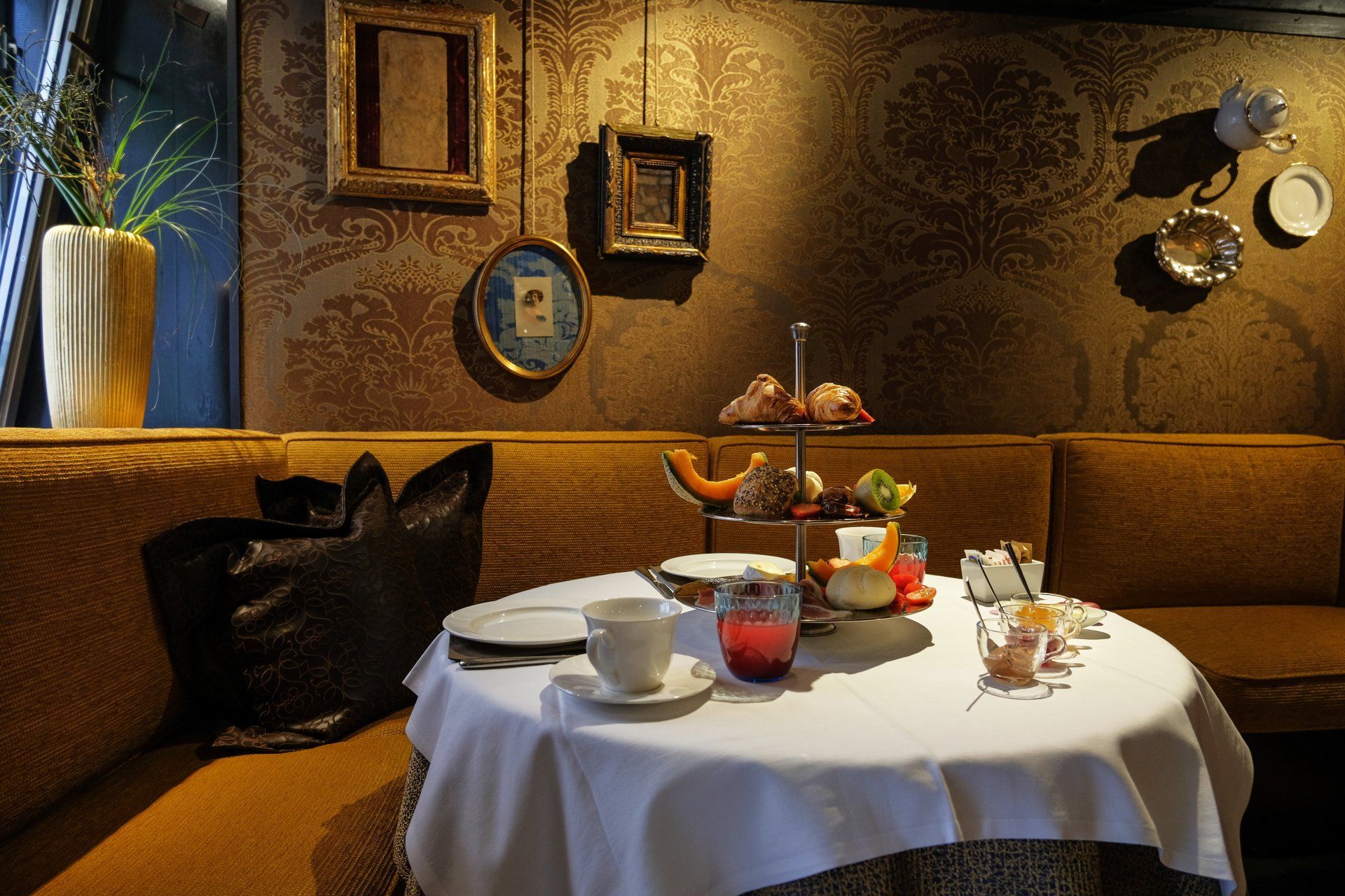 Tavolo apparecchiato per il tè in una stanza accogliente e decorata, con cibo disposto su un'alzata a più livelli.