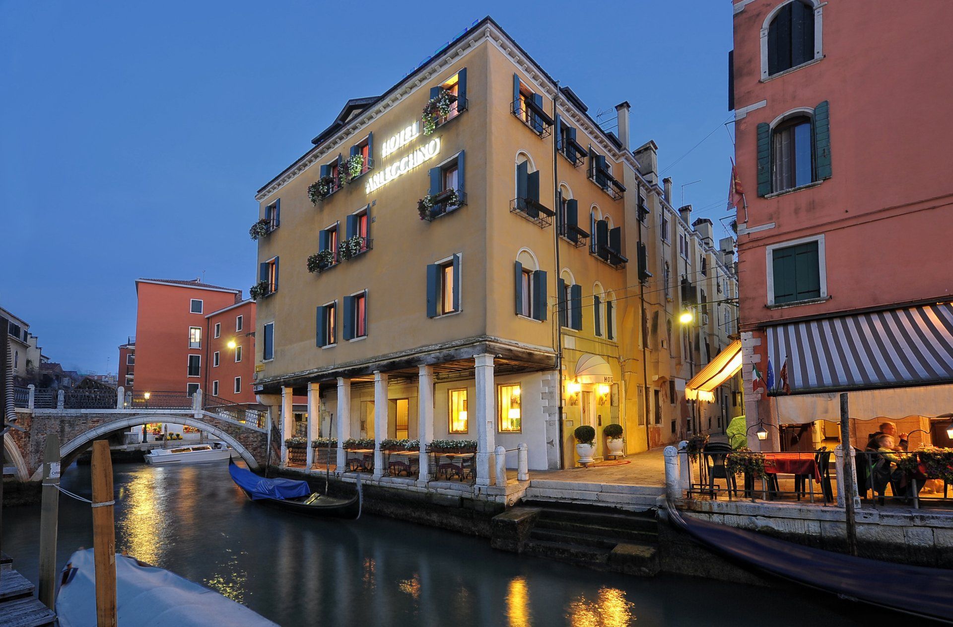 Hotel a Venezia lungo un canale, con ristorante e gondola, al tramonto.
