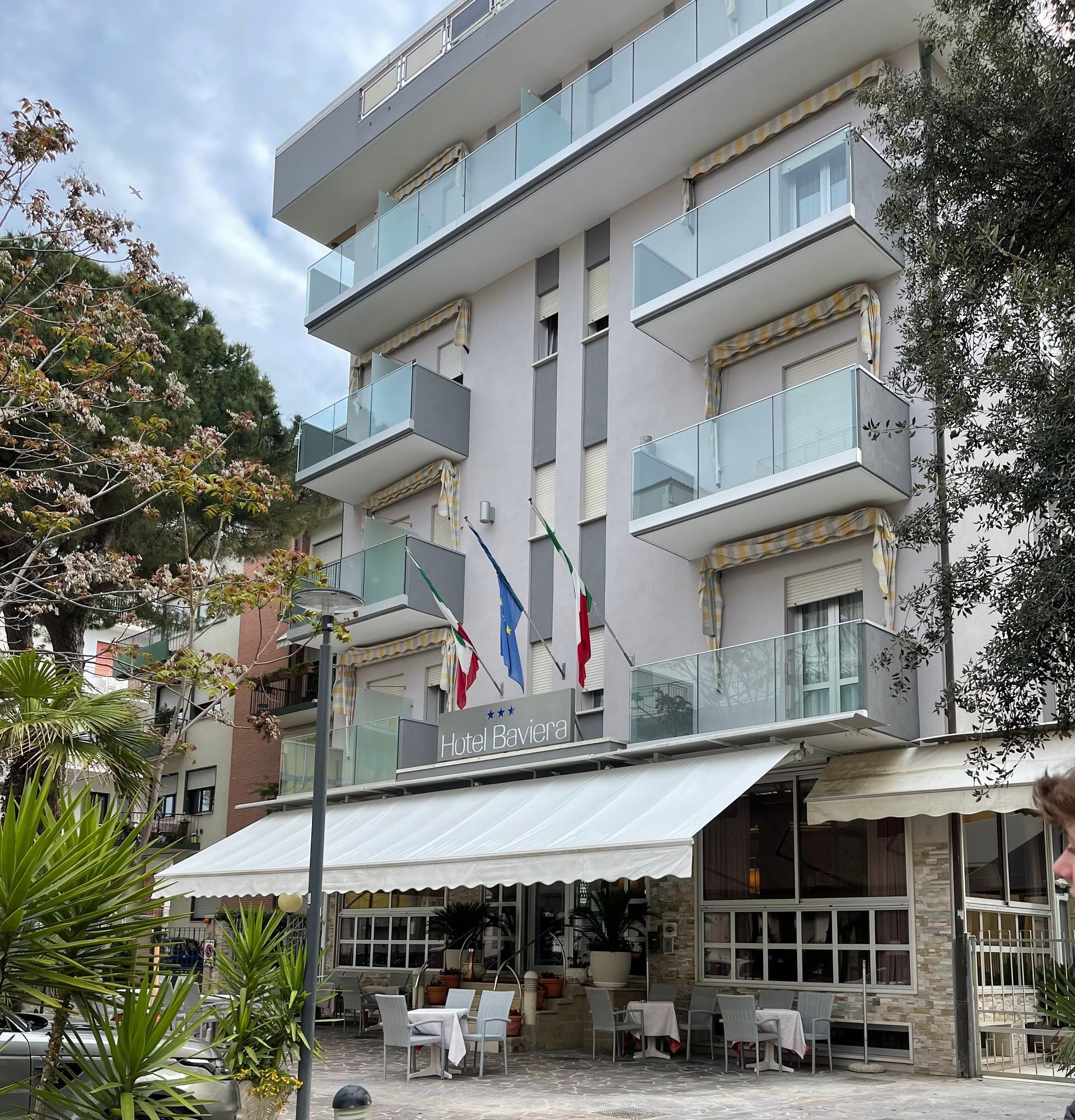 Hotel con bandiere, sala da pranzo all'aperto e balconi.