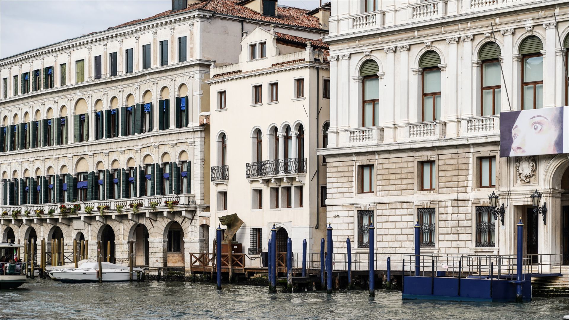 Edifici lungo un canale a Venezia, Italia, con acqua blu e pali di attracco.