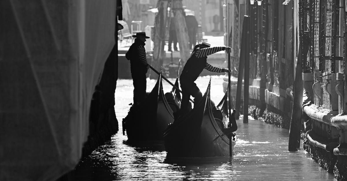 Gondolieri su barche a Venezia, Italia. Un uomo con un cappello, l'altro con un'asta. Bianco e nero.