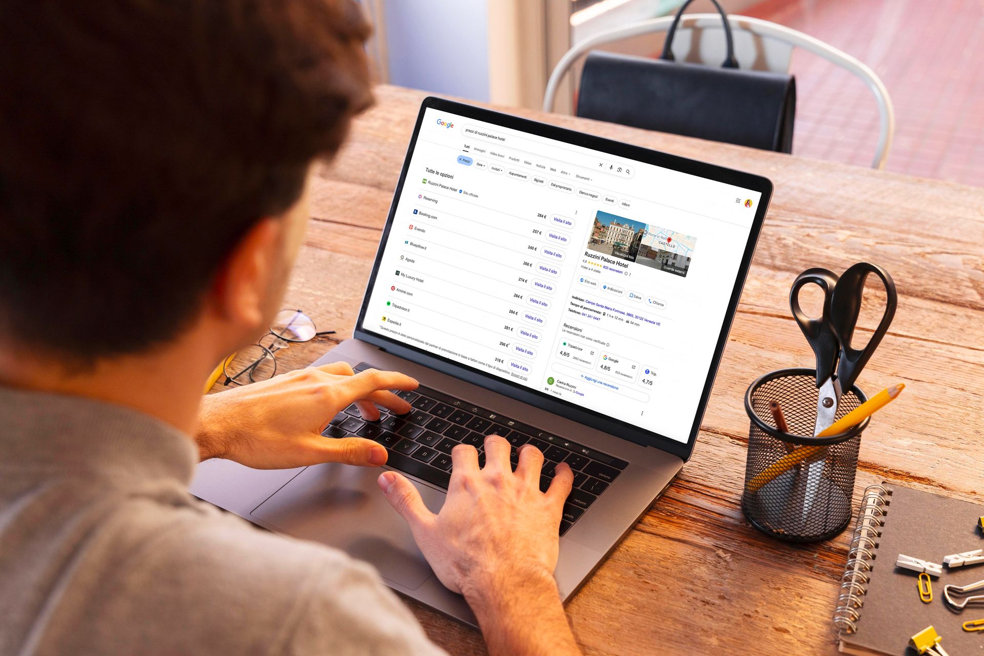 Persona che scrive su un computer portatile seduto a una scrivania di legno, guardando una pagina web