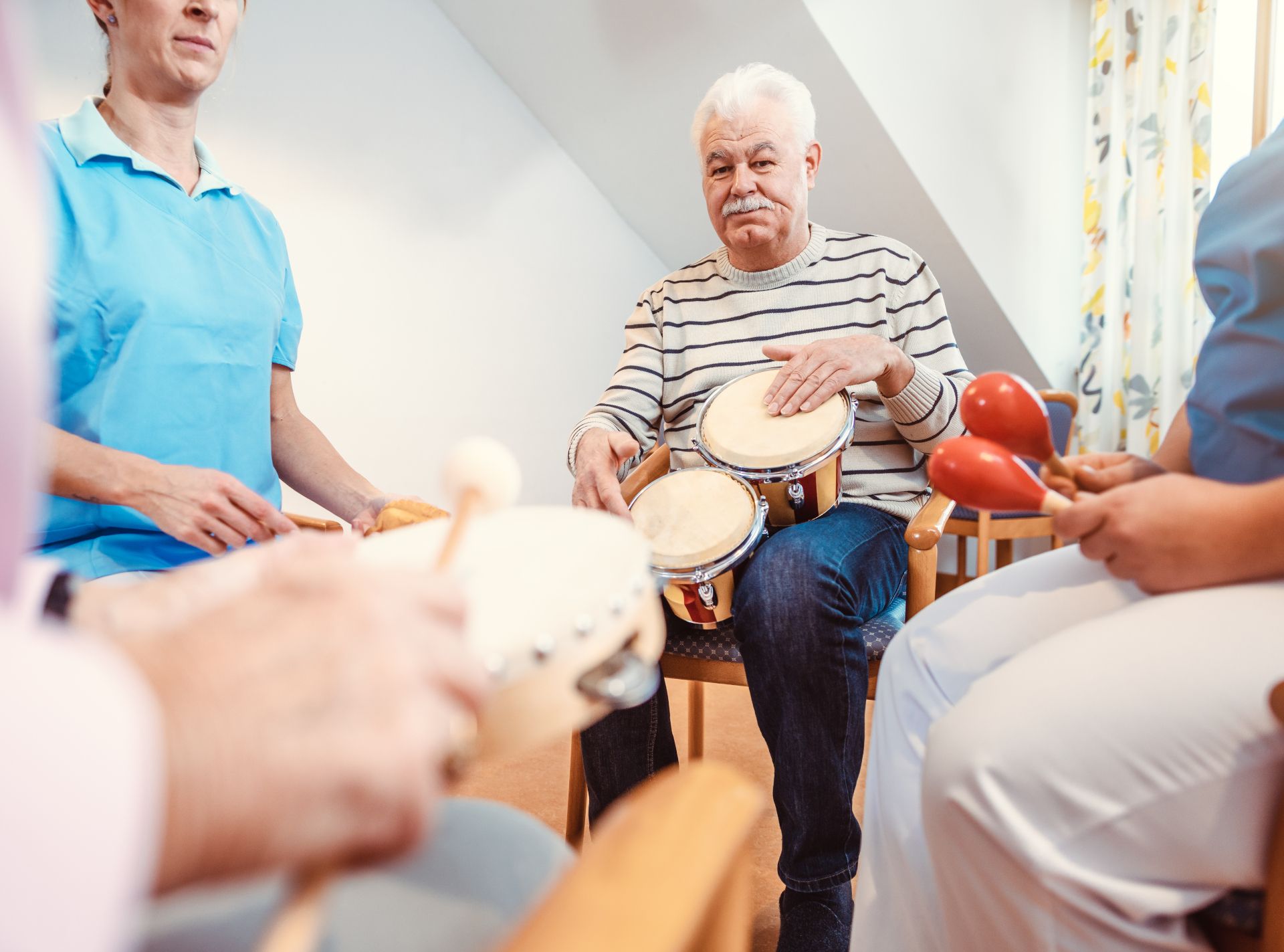 People playing hand drums in a bright room, seated in a circle during a music session