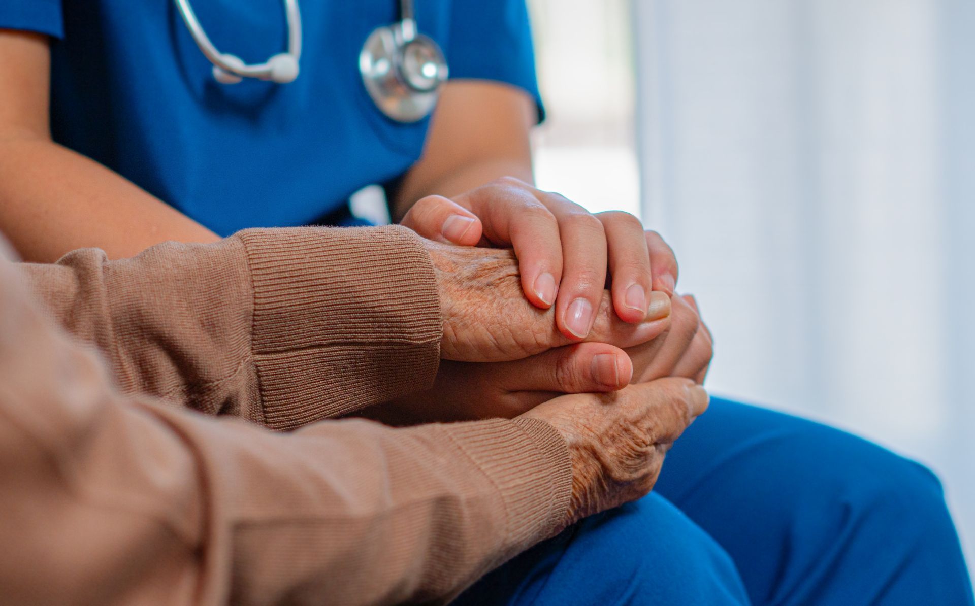 Healthcare worker holding a patient’s hand in a supportive gesture