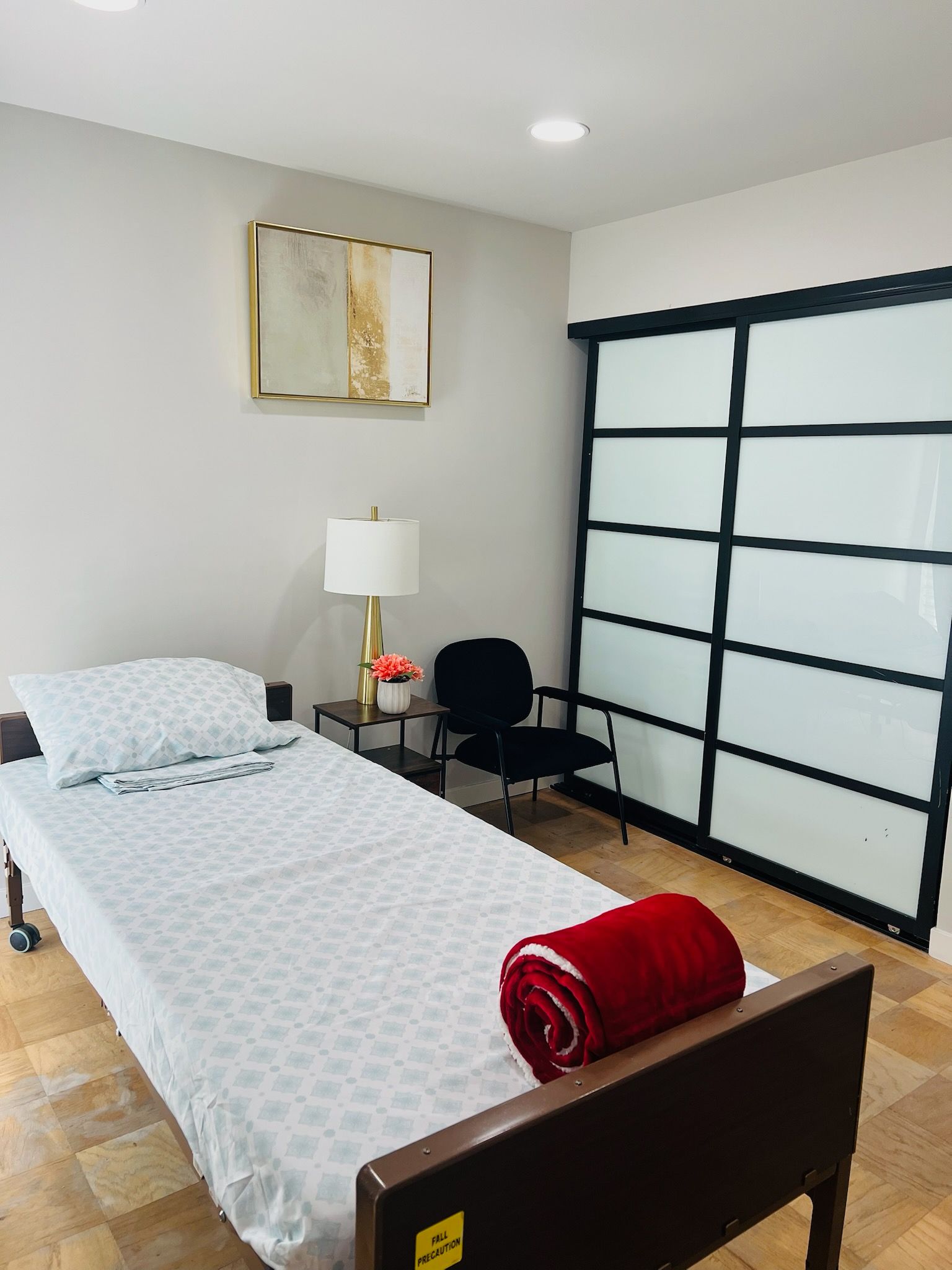 Minimal bedroom with single bed, desk lamp, chair, and black sliding closet doors