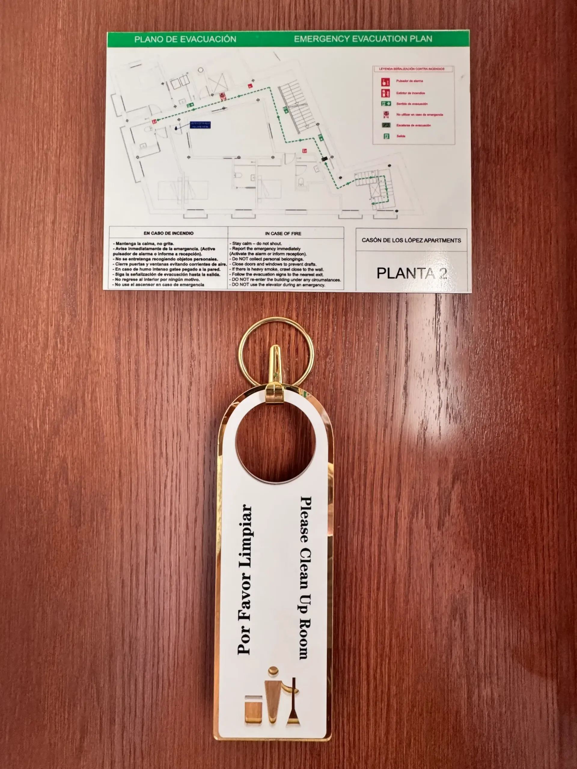 Un cartel de limpieza de habitaciones de hotel colgado en una puerta de madera, encima de un plano del piso etiquetado como 