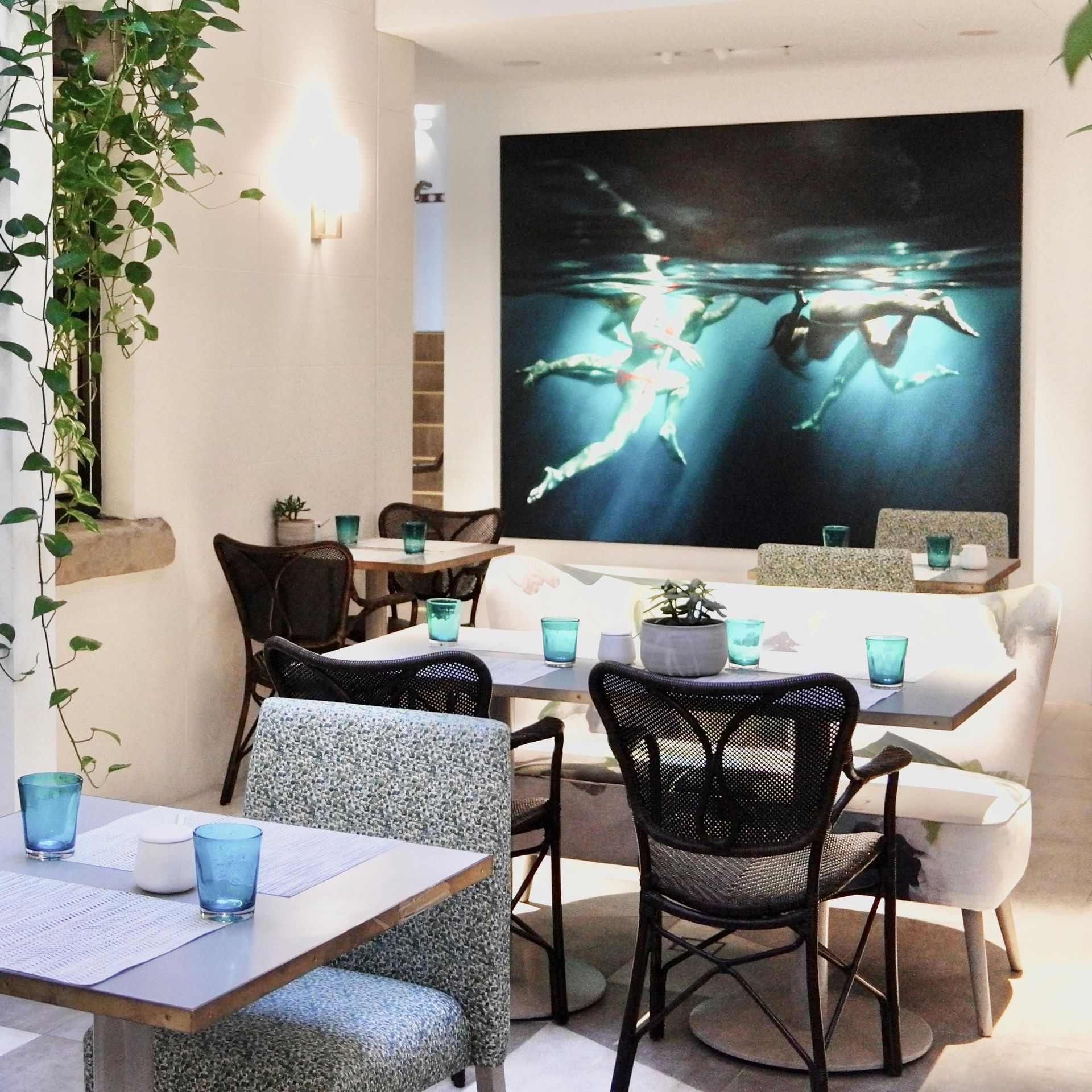 A dining room with tables and chairs and a painting on the wall