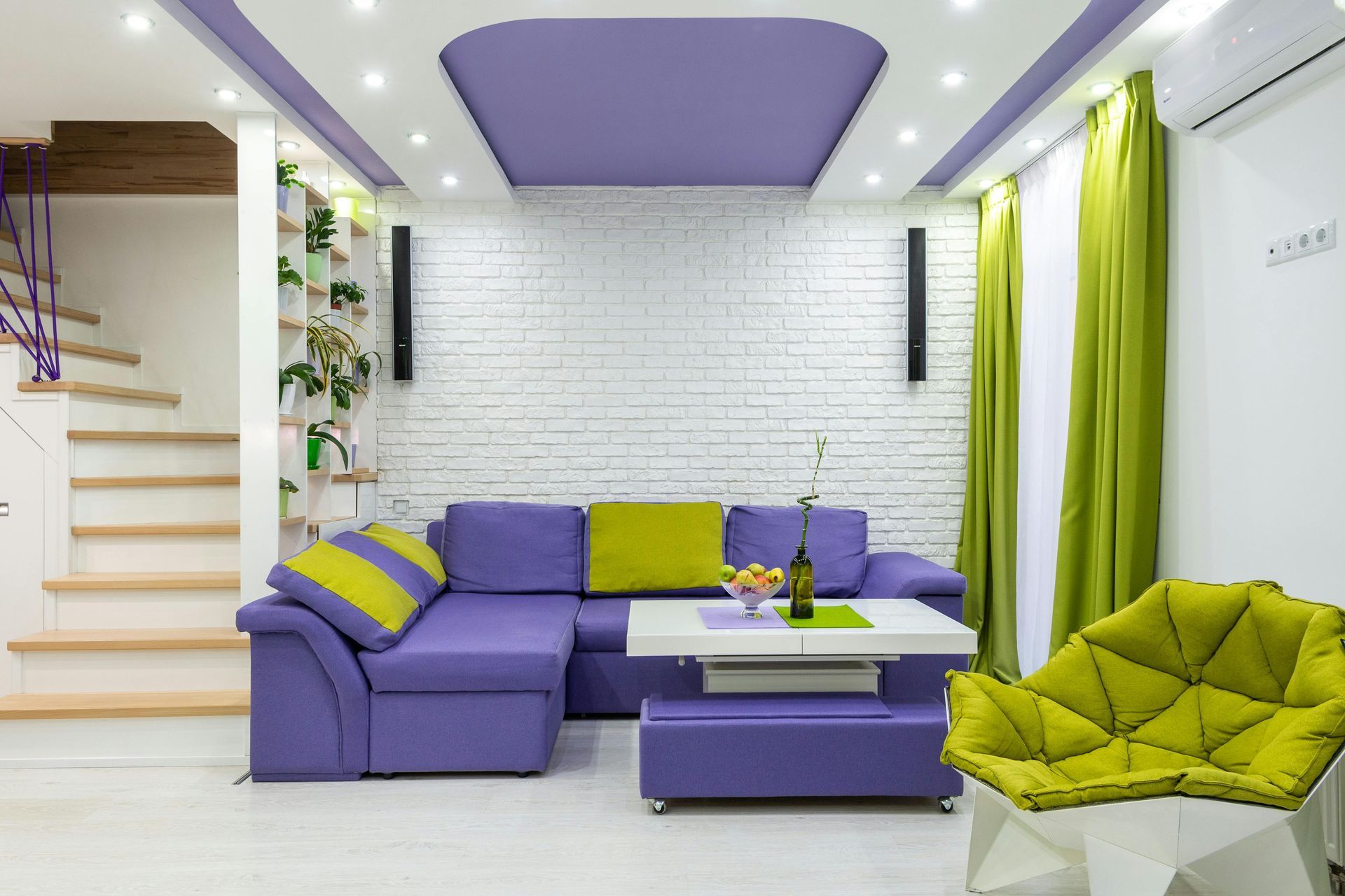 A living room with purple furniture and green chairs