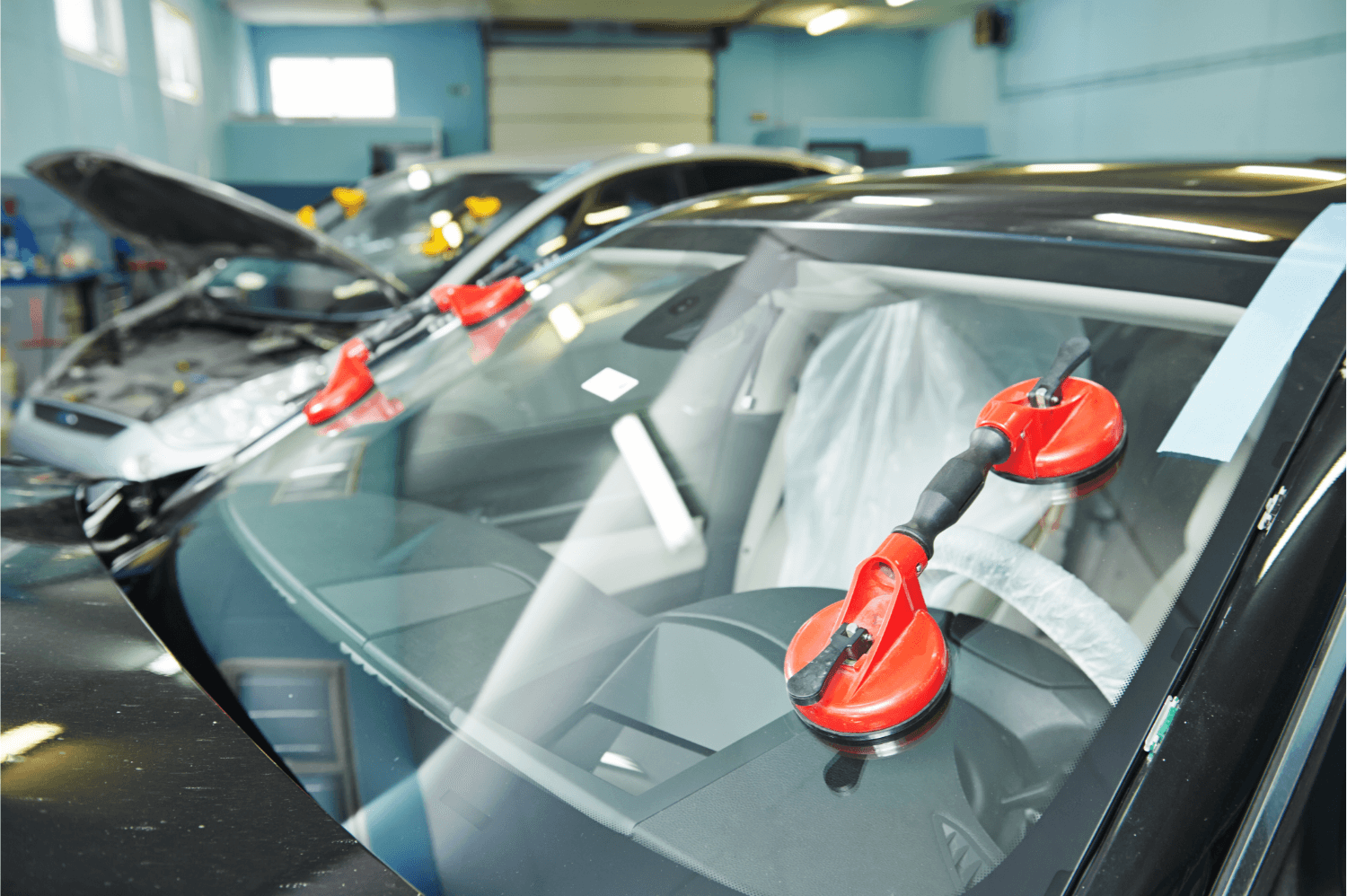 Car windshield repair with red suction tools on cracked glass in a garage