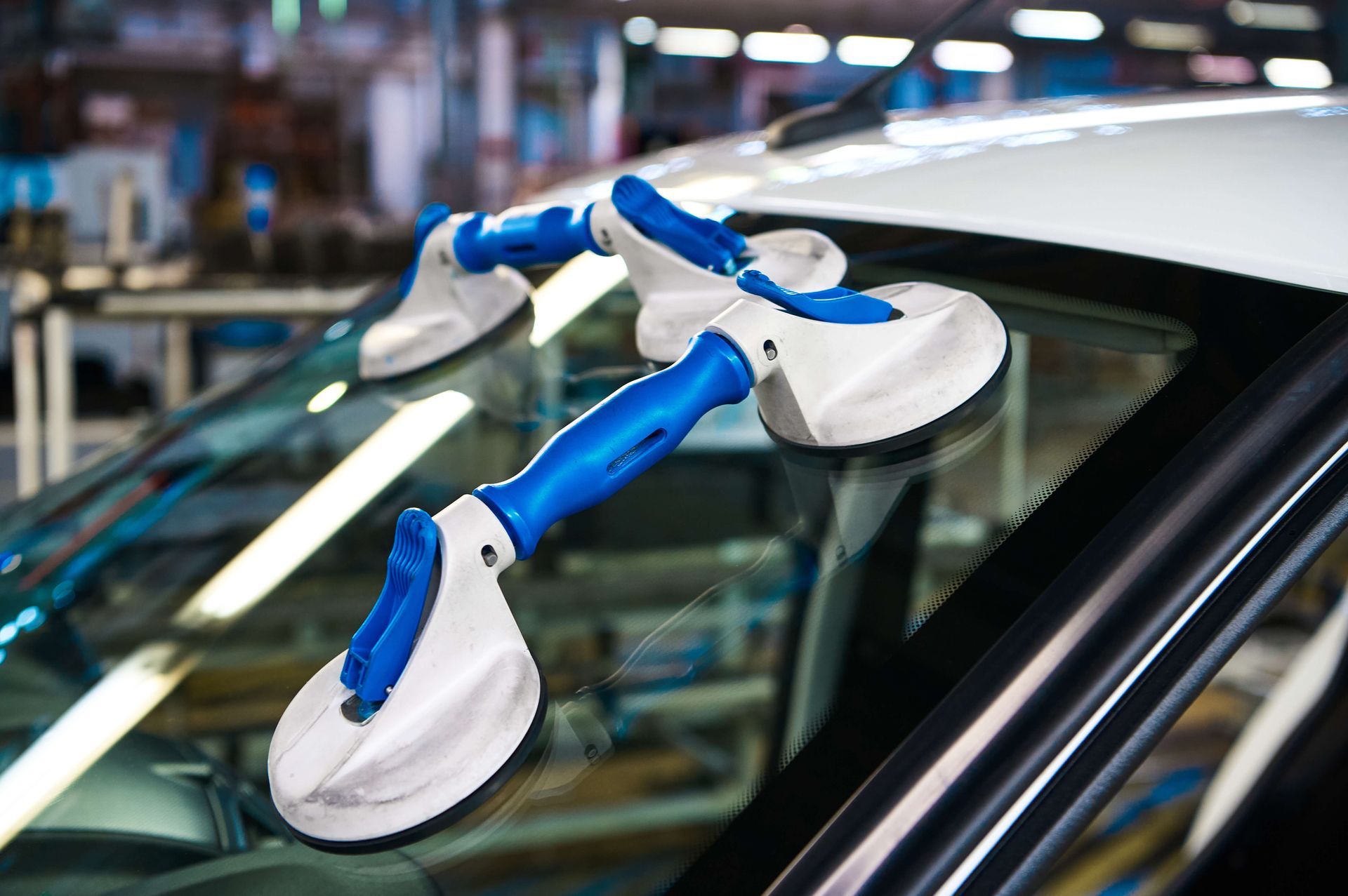 Robot arms working on a car windshield in an automotive assembly line
