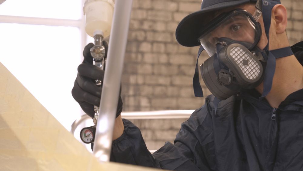 Person In Respirator And Safety Glasses Spraying Paint — TMP Painting Services in Beaconsfield, QLD