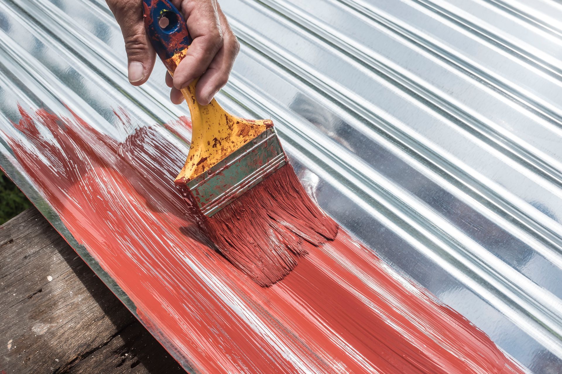 Person Painting Red Paint On A Corrugated Metal Surface With A Brush — TMP Painting Services in Beaconsfield, QLD