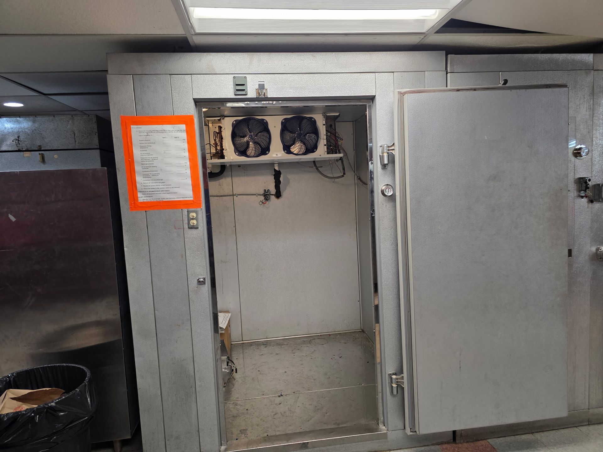Open electrical cabinet with fans and a highlighted note on the left side.