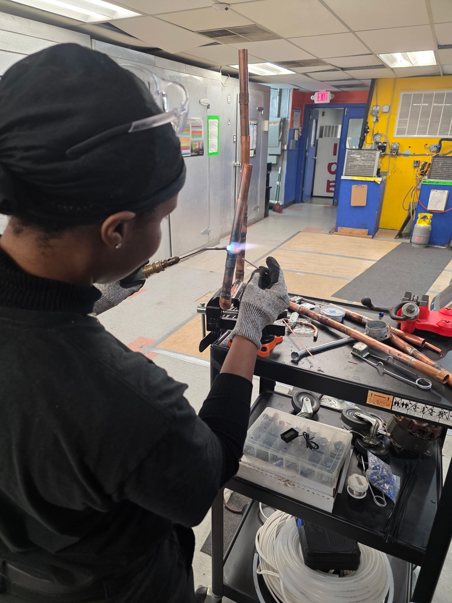 Person operating a robotic arm in a workshop, with tools and equipment in the background.