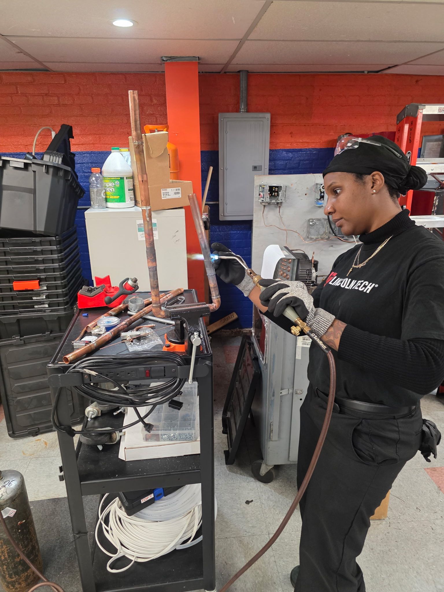 Technician using a welding torch at a workbench in a garage or repair shop