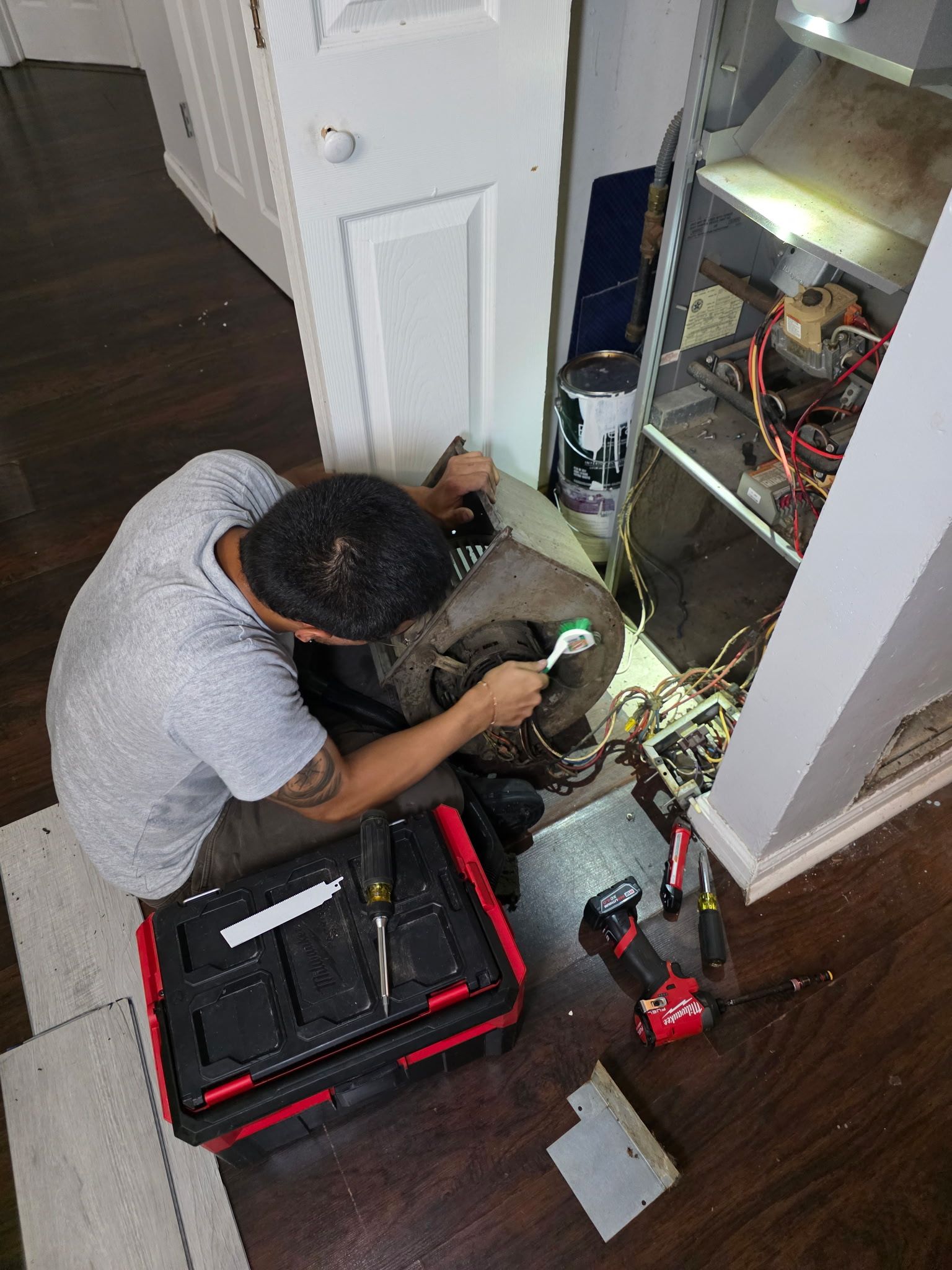 Technician repairing electrical wiring in a hallway closet with tools and open equipment case on the floor