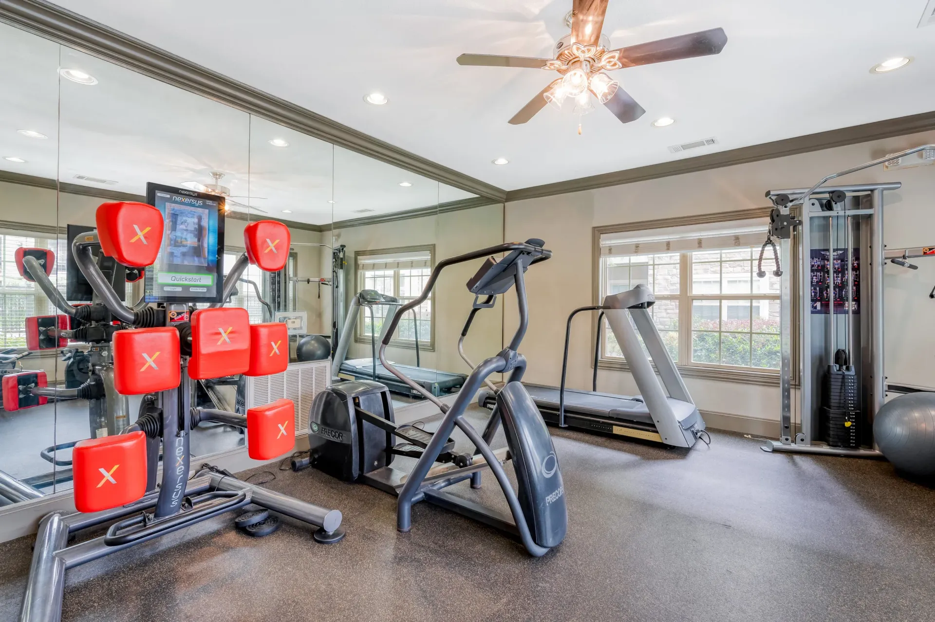 Community gym with cardio machines, weights, and mirrored walls.