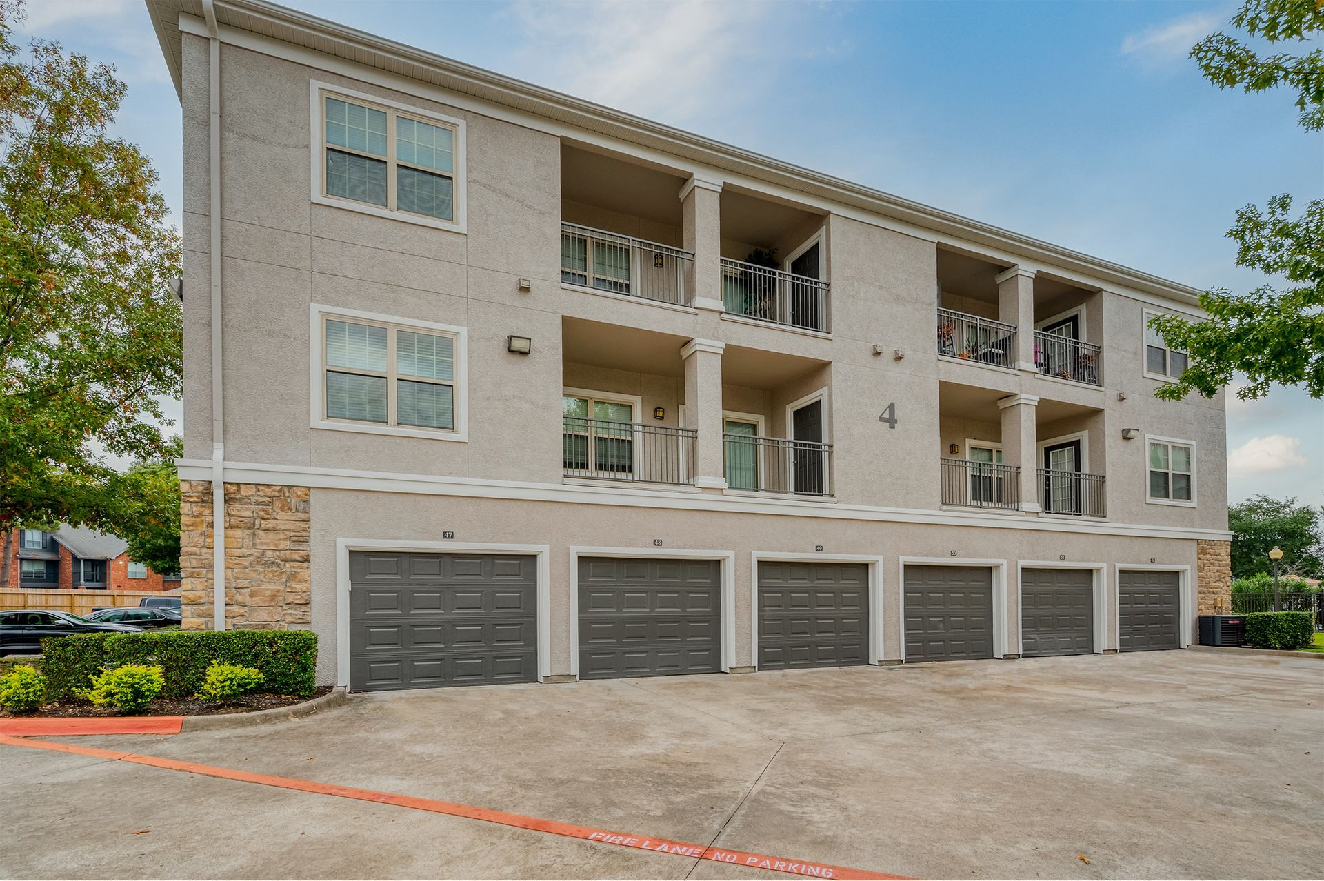 Exterior view of a multi-family building with ground-level garages and upper-floor balconies.