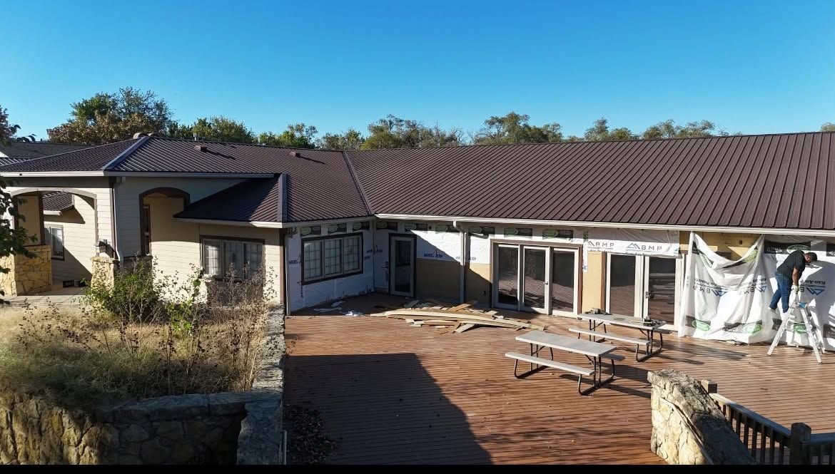 Single-story house with a brown roof and brick patio under clear blue sky