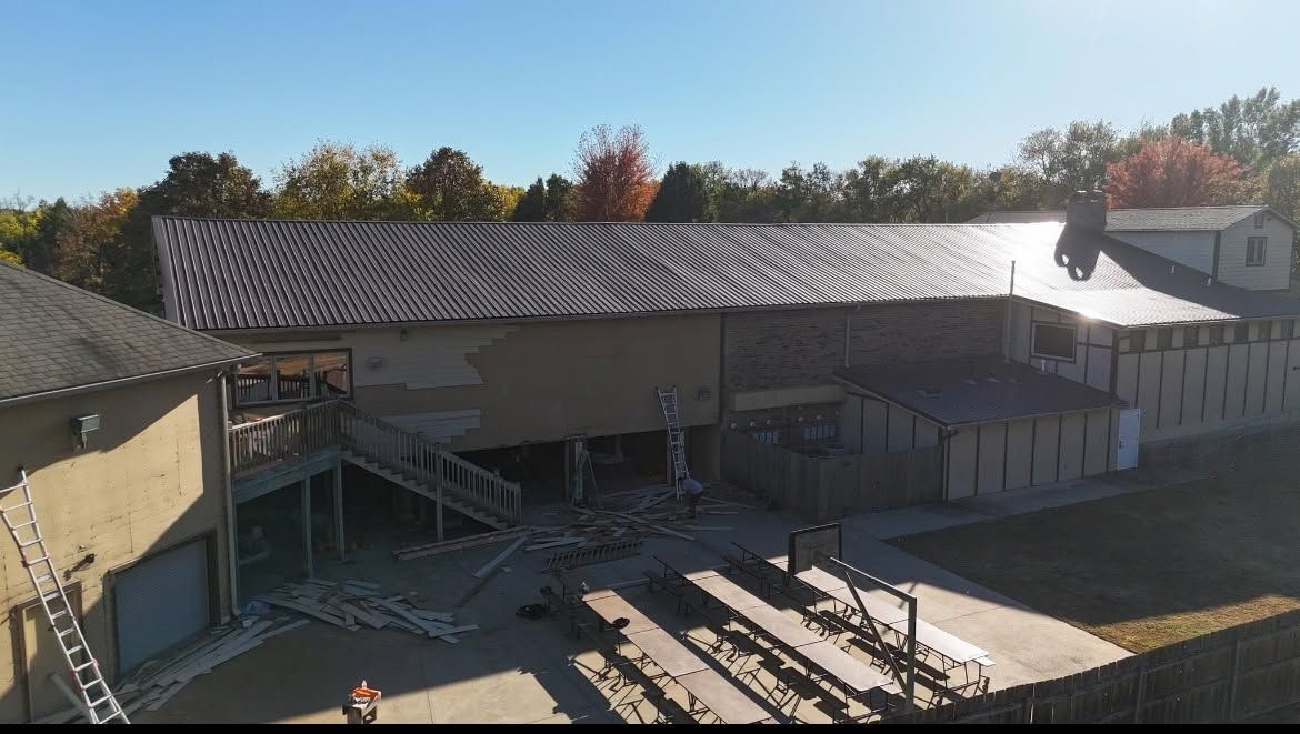 Large outdoor amphitheater with a covered stage, tiered seating, and trees in the background.