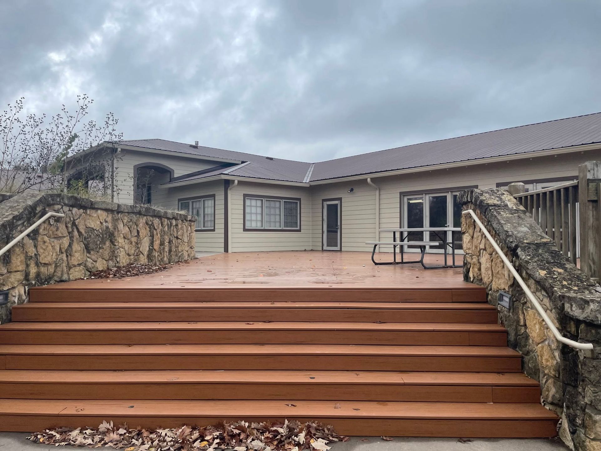 Front steps leading to a single-story house with a tan deck and cloudy sky