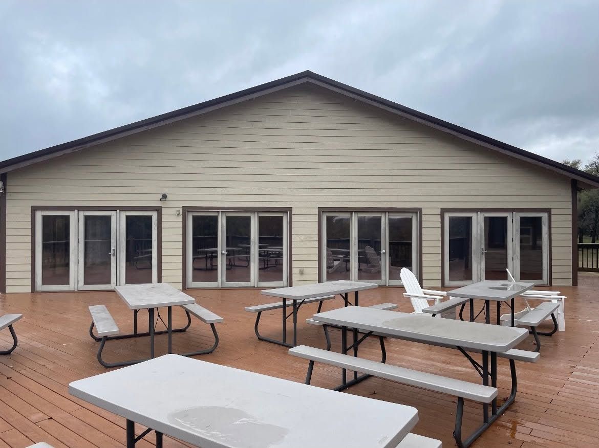 Outdoor patio with picnic tables in front of a beige building under a cloudy sky