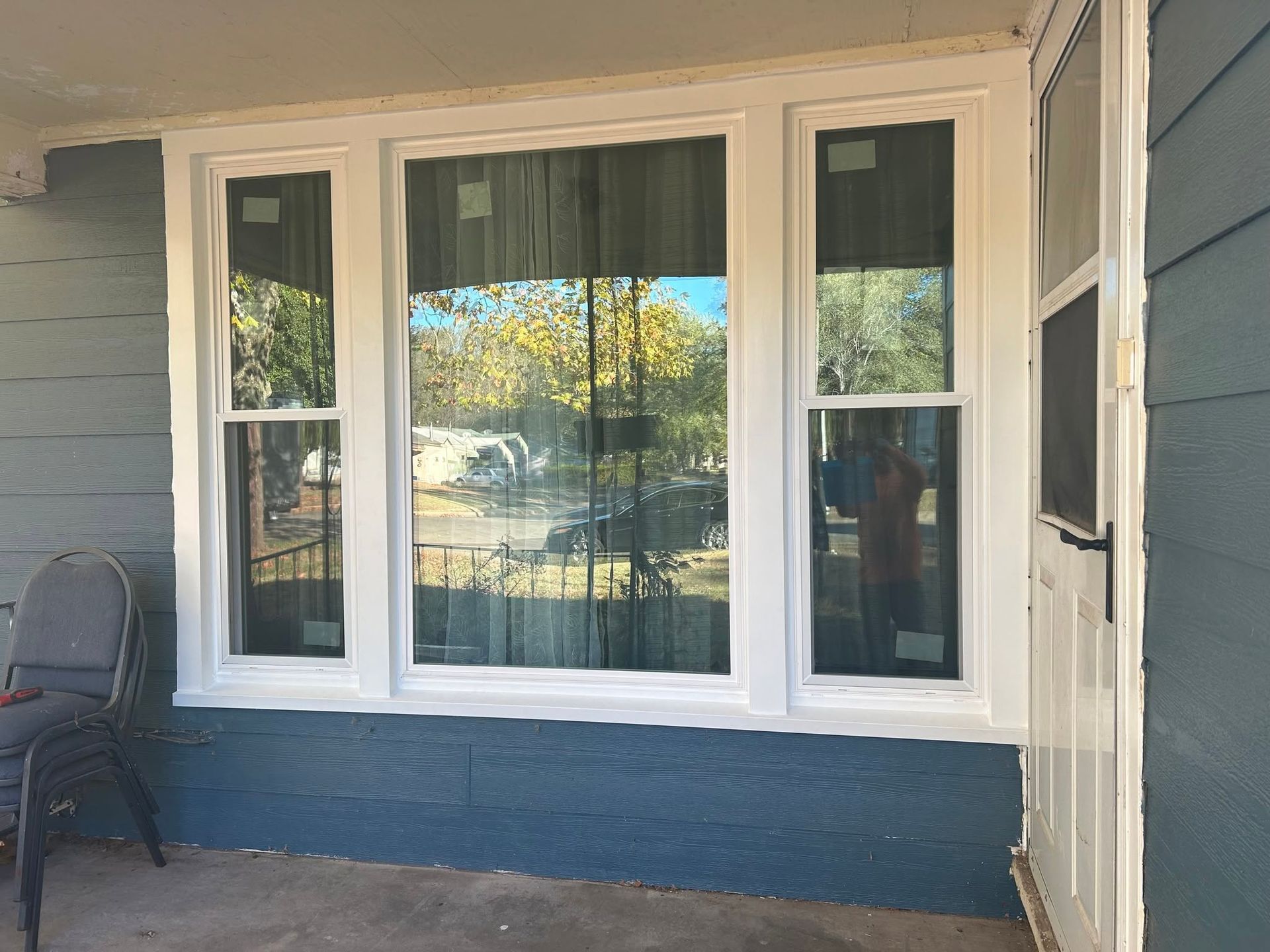 White-trimmed porch with three windows and a blue lower exterior wall, seen from outside