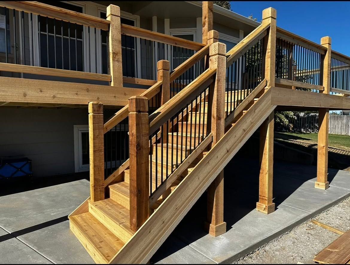 Wooden staircase with railing leading to an upper deck beside a house on a sunny day