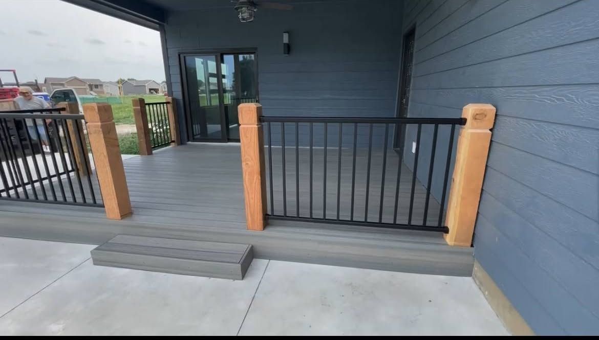 Front porch with dark gray railings and wooden posts, leading to a glass door entrance.