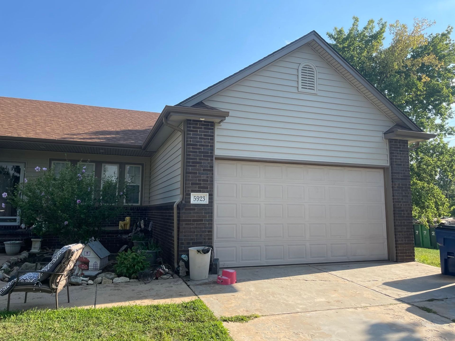 Suburban house exterior with a two-car garage, driveway, and front porch in daylight