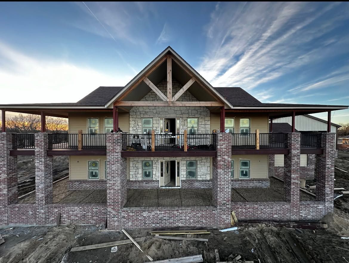 Stone lodge with a large wooden gable roof and wraparound balconies against a blue sky