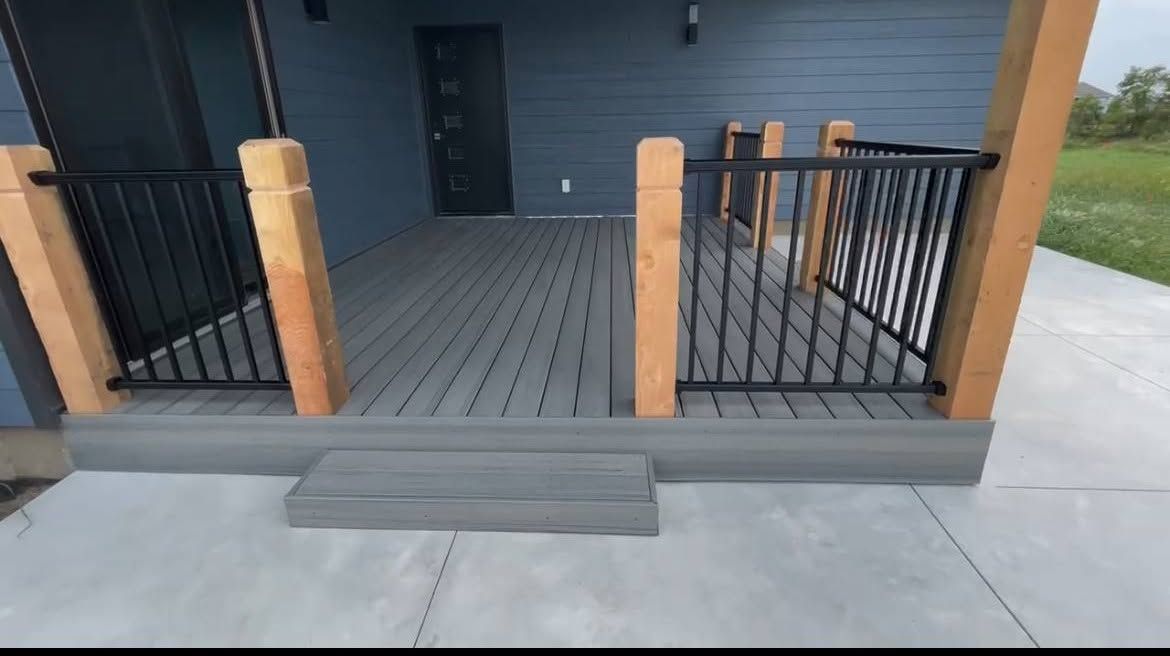 Front porch with dark railings, wood posts, and a single step up to a blue house entrance.
