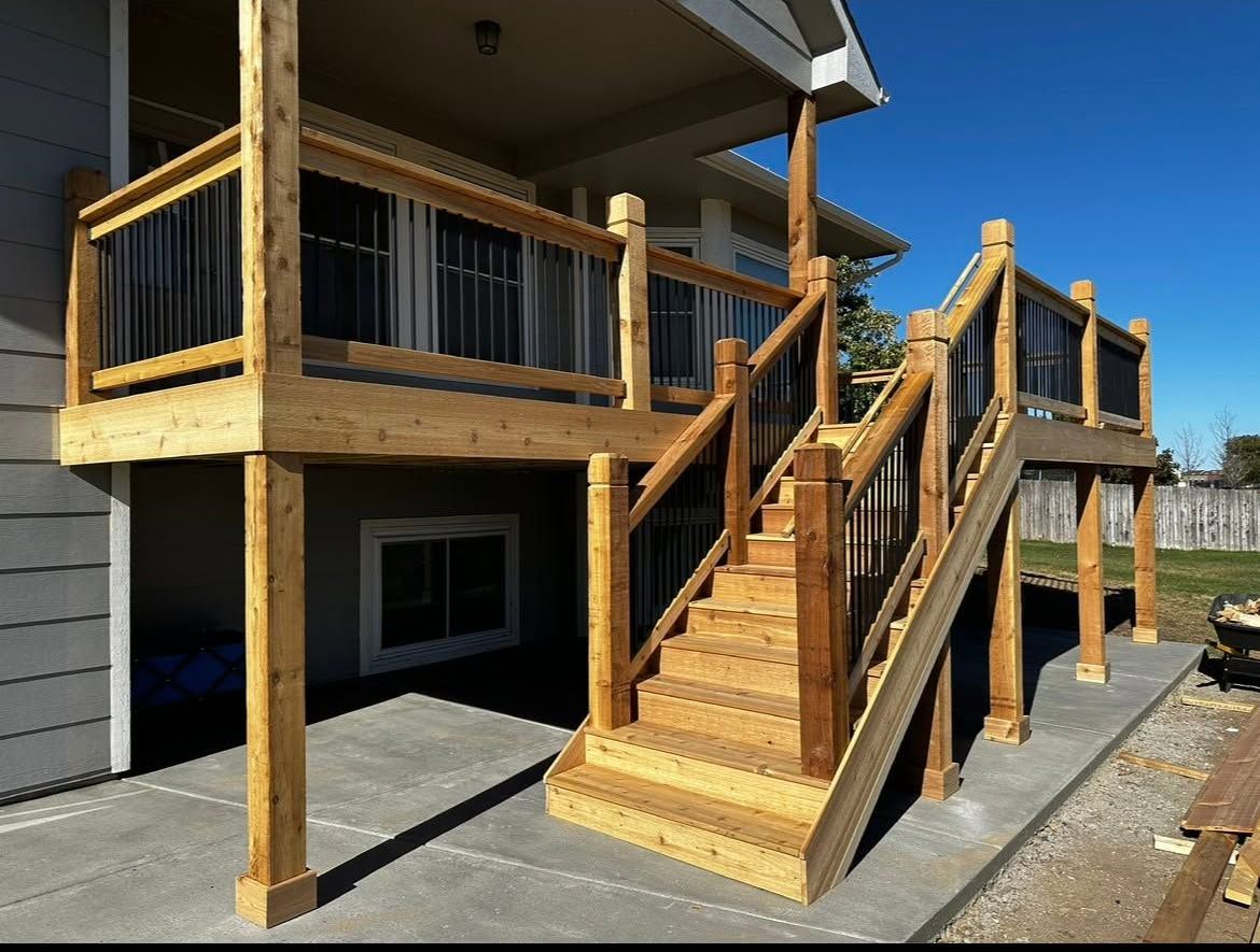Wooden deck stairs and railings on a house exterior with a covered porch and garage below