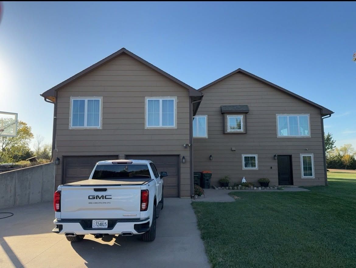 Two-story tan suburban house with a white pickup truck parked in the driveway under a clear sky