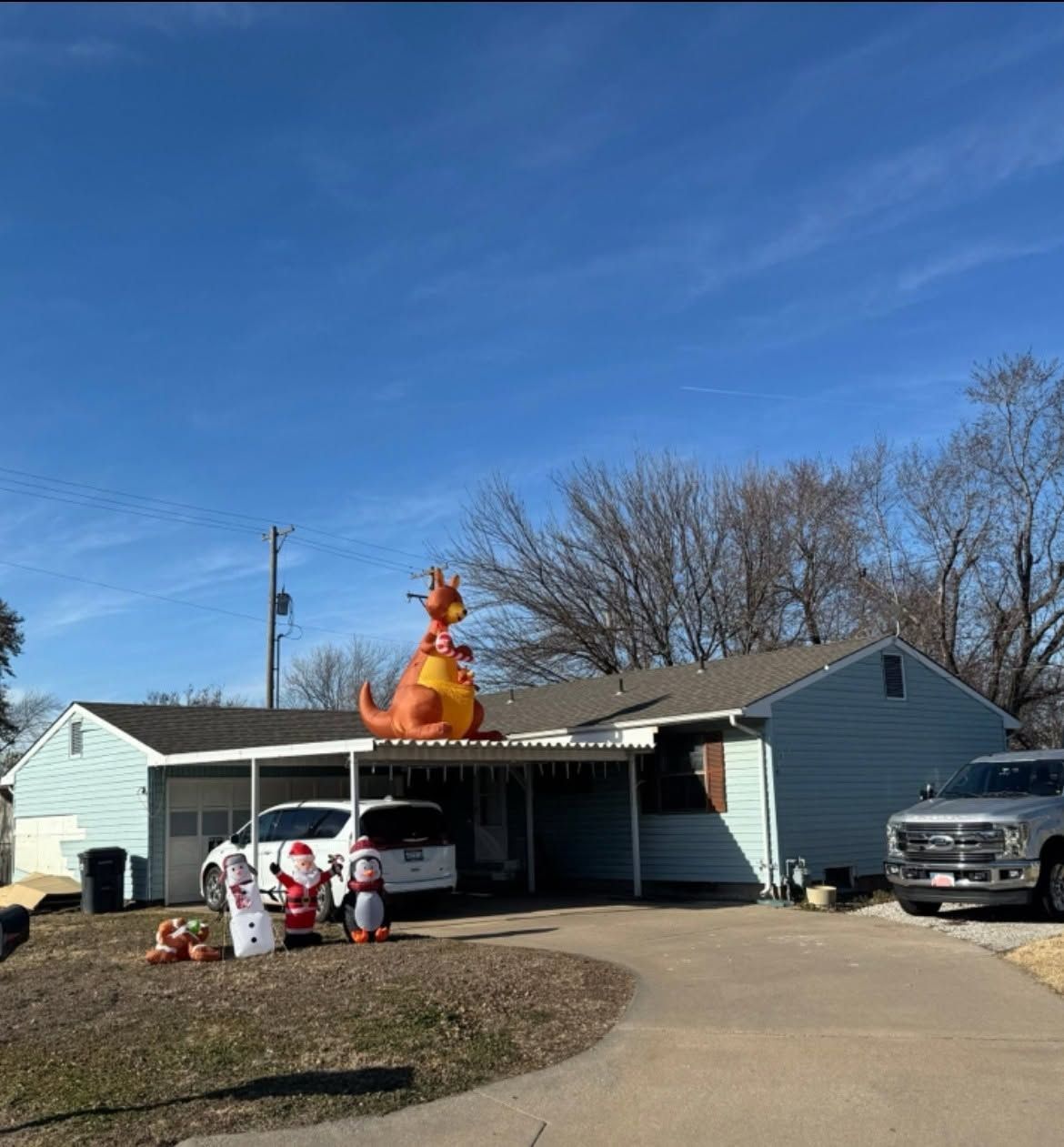 House with a giant orange inflatable cat on the roof, holiday decorations, and a truck in the driveway