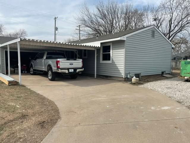 Gray house with a carport and a white pickup truck parked on a curved driveway