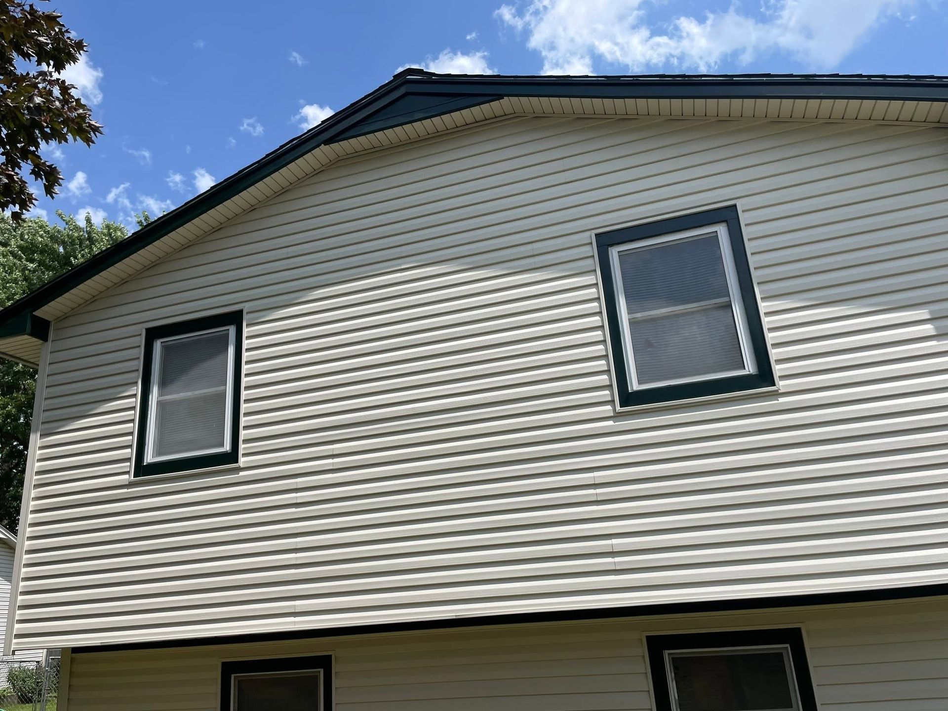 Side view of a white house with gray roof and two windows against a blue sky