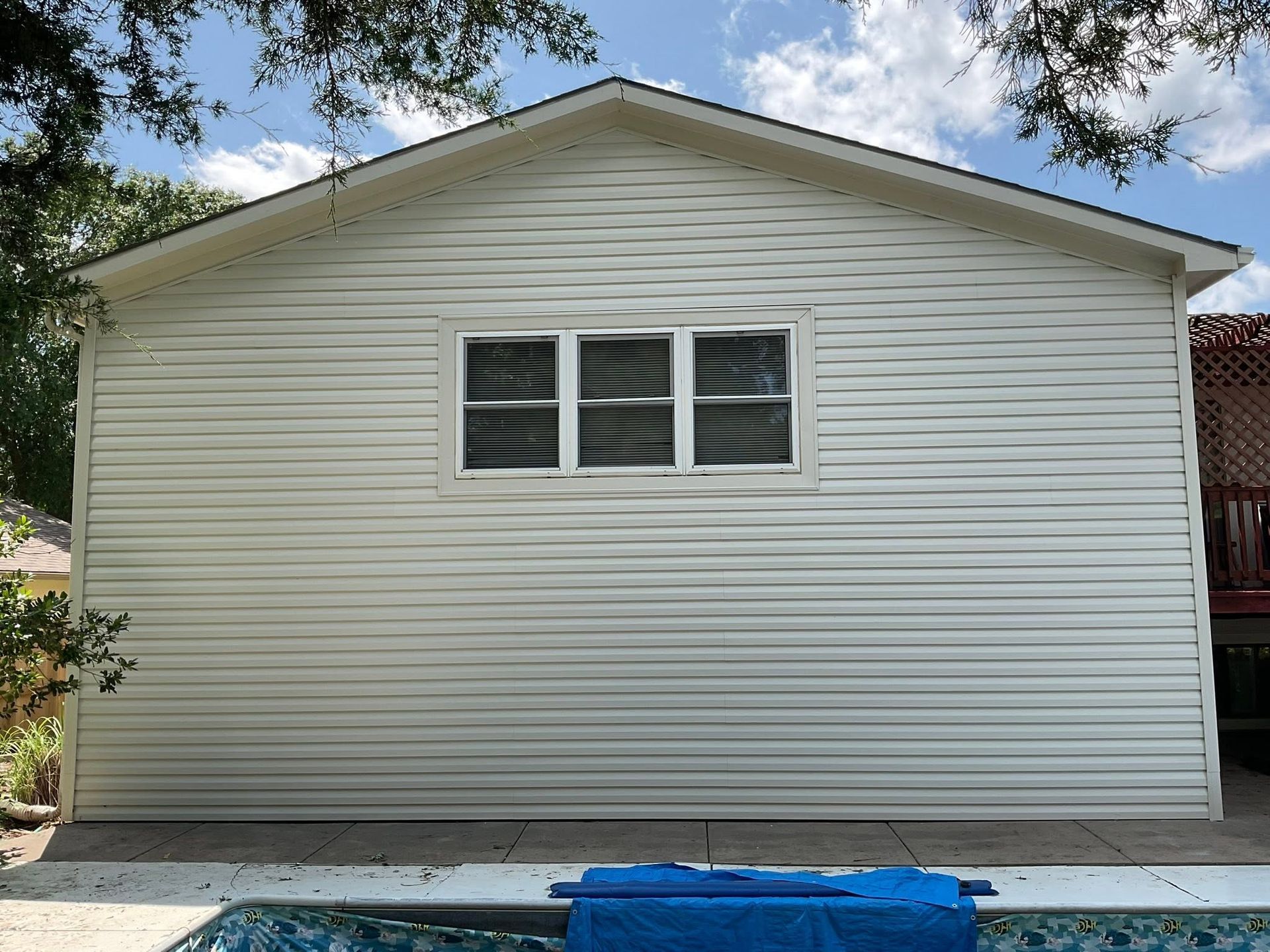 White house exterior with horizontal siding and a three-panel window